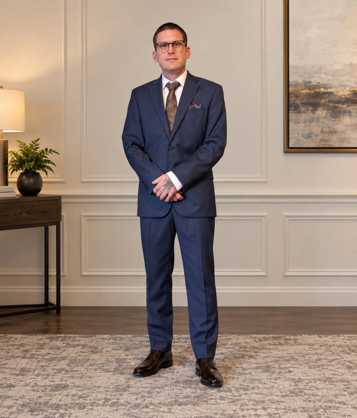 Dré McCormick wearing glasses and a navy suit with a patterned tie.